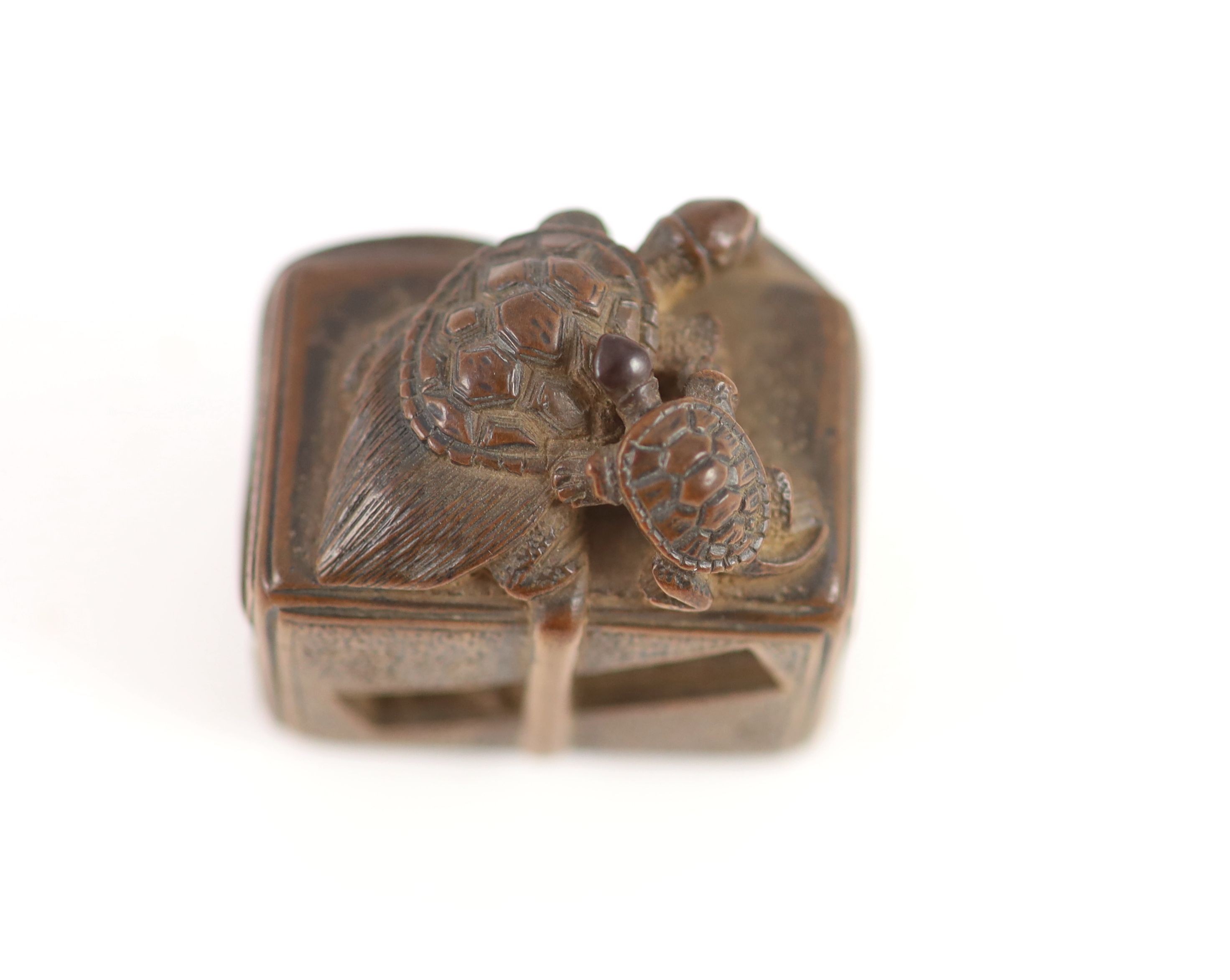 A Japanese boxwood netsuke of a minogame and young perched on the top of a fubako, signed Gyokoku, 19th century, 3.5cm wide